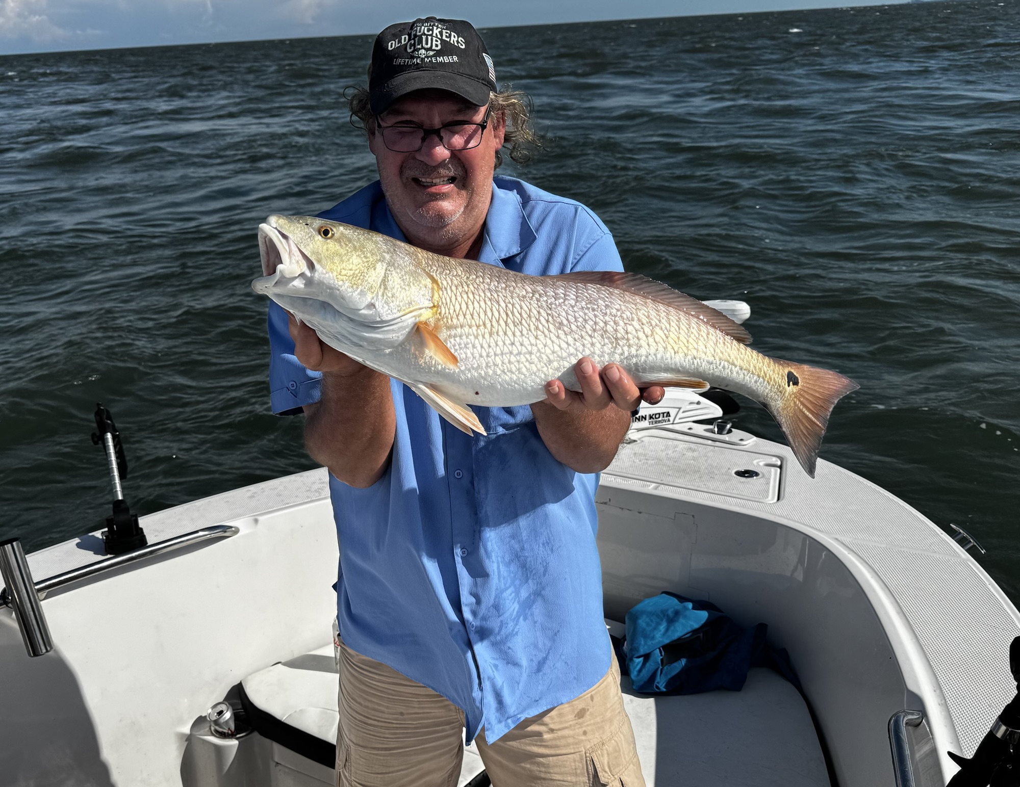 Smiling angler holding a redfish on the water